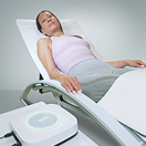 Frau liegt entspannt auf weißer Therapieliege in Rückenlage