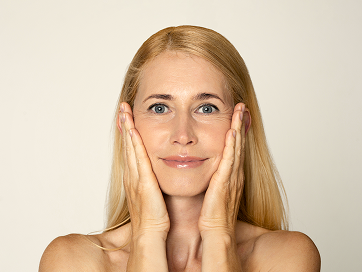 Frau berührt ihr Gesicht mit beiden Händen